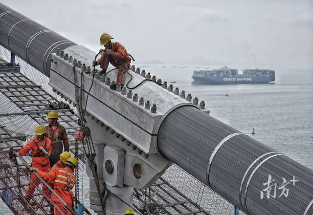 正在施工中的建設(shè)者身后，海上船舶往來(lái)不斷。  