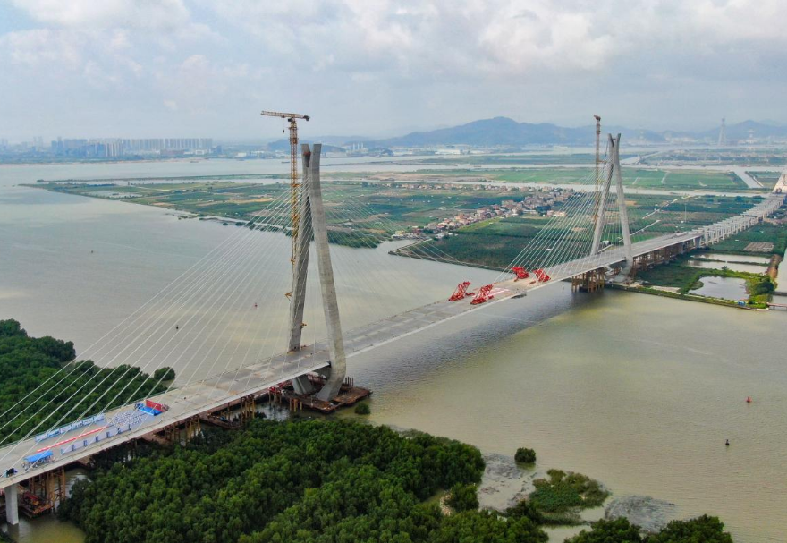南中高速連通廣州、中山、深圳三市，是國家高速公路網(wǎng)G2518和廣東省高速公路網(wǎng)S78的重要組成部分，也是粵港澳大灣區(qū)重大交通基礎設施項目。其中的洪奇門特大橋全長1126米，為主跨520米的雙塔雙索面鋼箱梁斜拉橋，是南中高速項目的關鍵控制性工程。2023年5月21日上午，南中高速洪奇門特大橋順利合龍，實現(xiàn)了廣州、中山兩市實現(xiàn)跨江“牽手”。圖為南中高速洪奇門特大橋。