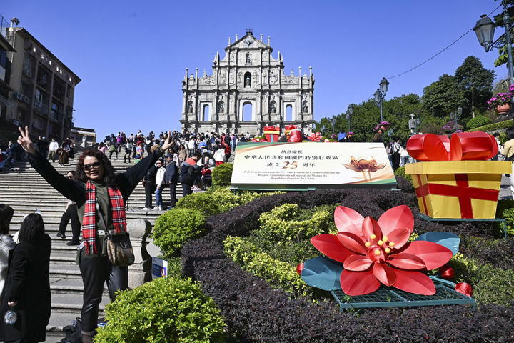 游客在澳門大三巴牌坊慶祝布景旁留影（2024年12月18日攝）。新華社記者 程一恒 攝