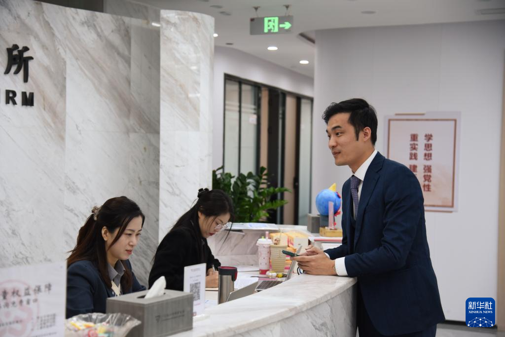 澳門(mén)律師阮嘉銳（右）在和同事交談（12月19日攝）。新華社記者 洪澤華 攝