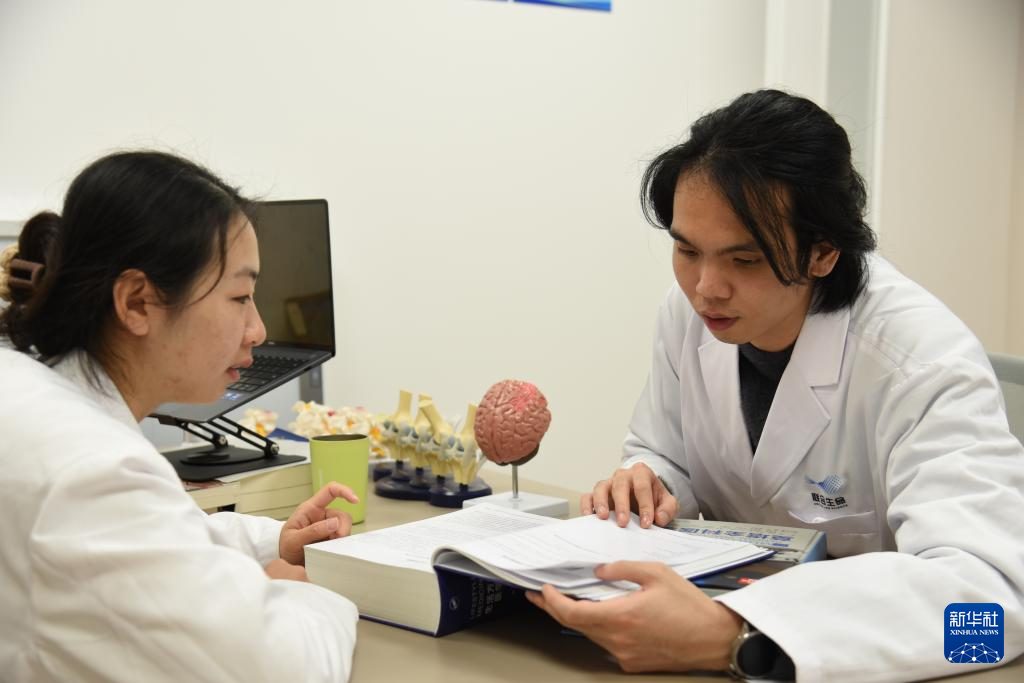 澳門醫(yī)生繆永銳（右）和同事進行交流（12月17日攝）。新華社記者 洪澤華 攝