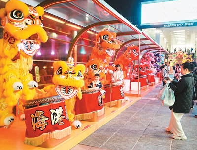 近日在香港維多利亞港畔，游客和醒獅合影。新華社記者 褚萌萌攝