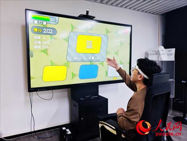 廣州琶洲實驗室工作人員演示腦機接口設備如何操作專注力訓練游戲。人民網(wǎng) 樸馨語攝