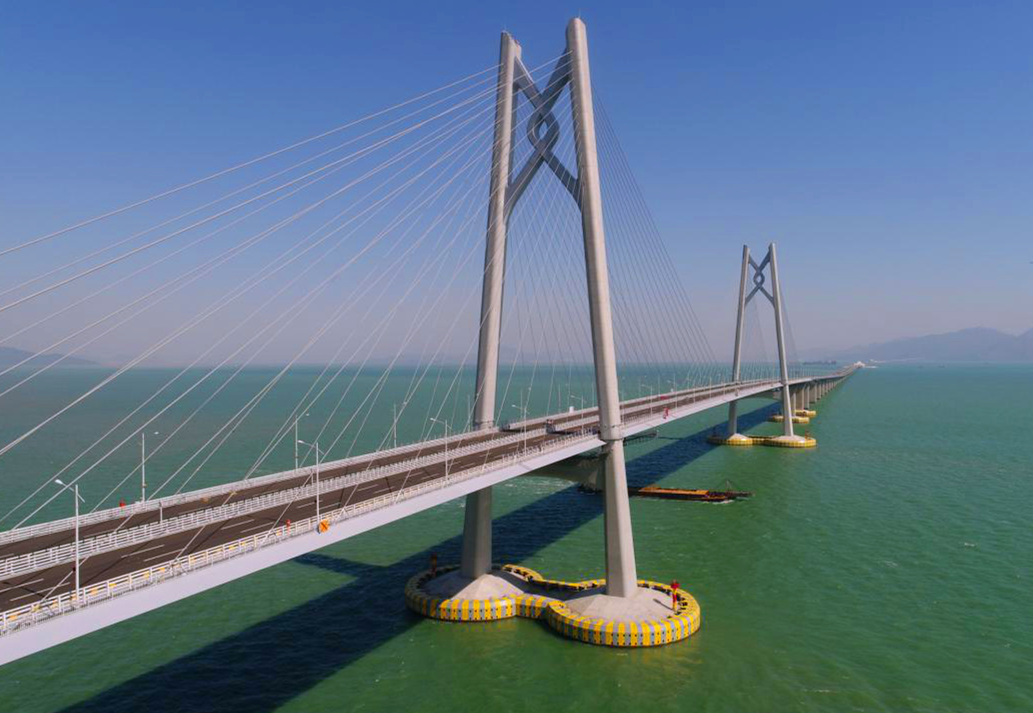 港珠澳大橋主體工程實行橋、島、隧于一體，總長約29.6公里，穿越伶仃航道和銅鼓西航道段約6.7公里為隧道，東、西兩端各設置一個海中人工島（藍海豚島和白海豚島），猶如“伶仃雙貝”熠熠生輝；其余路段約22.9公里為橋梁，分別設有寓意三地同心的“中國結(jié)”青州橋、人與自然和諧相處的“海豚塔”江海橋，以及揚帆起航的“風帆塔”九洲橋三座通航斜拉橋。圖為寓意三地同心的“中國結(jié)”青州橋。